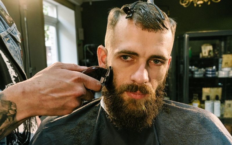 Barbier qui taille la barbe d'un client à la tondeuse