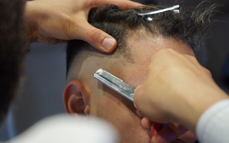 Barbier qui nettoie un dégradé à blanc au rasoir sur la nuque