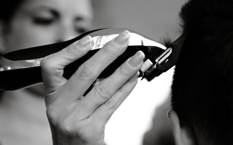 Tondeuse à cheveux en main pendant une coupe, en noir et blanc