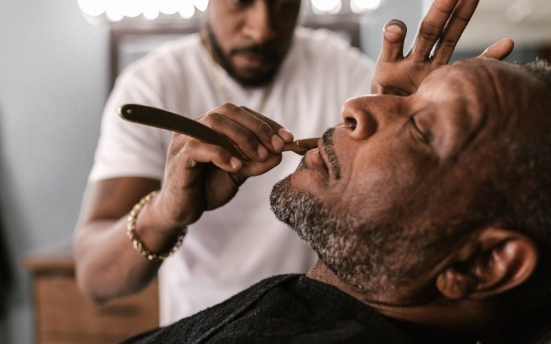Barbier qui rase un client au coupe-chou au salon