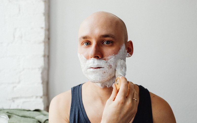 Homme au crâne rasé qui applique de la mousse à raser sur son visage