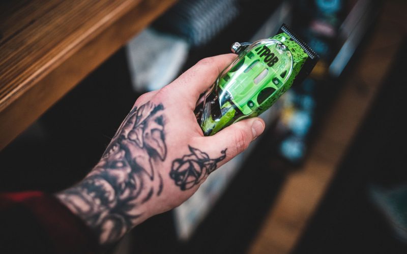 Main tatouée qui tient une tondeuse pour le corps