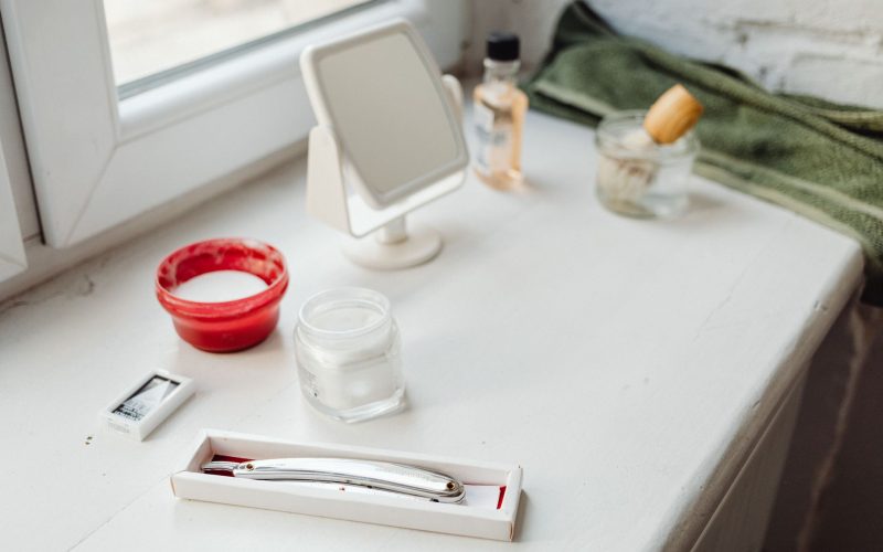 Rasoir, blaireau et produits de rasage posés près d'une fenêtre