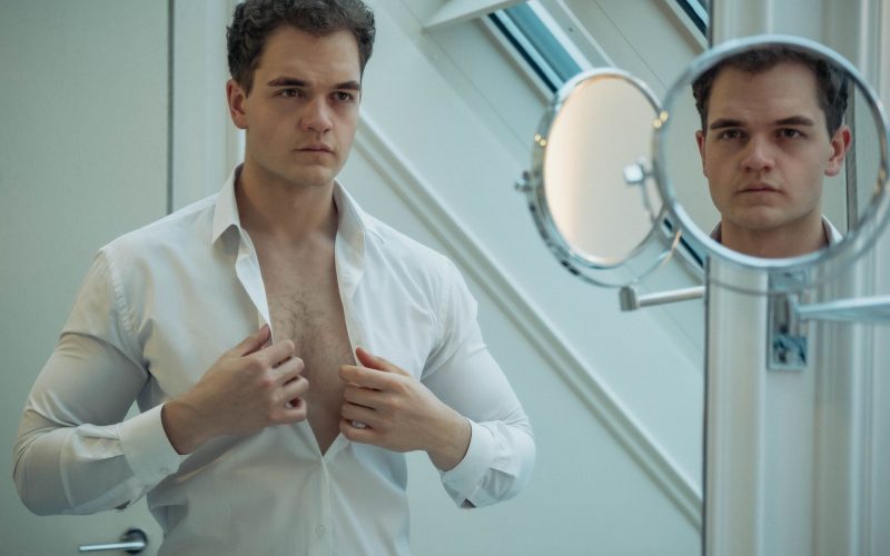 Homme qui ouvre sa chemise devant un miroir de salle de bain
