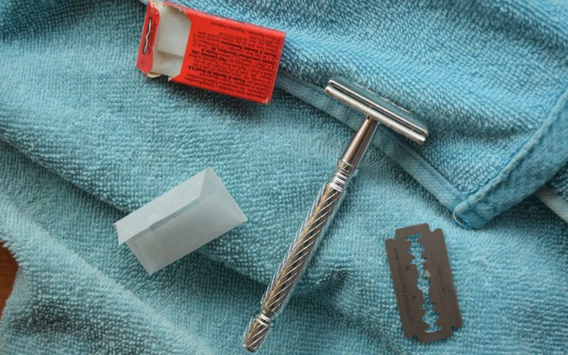 Rasoir de sûreté en métal, lames de rechange et boîte sur une serviette bleue