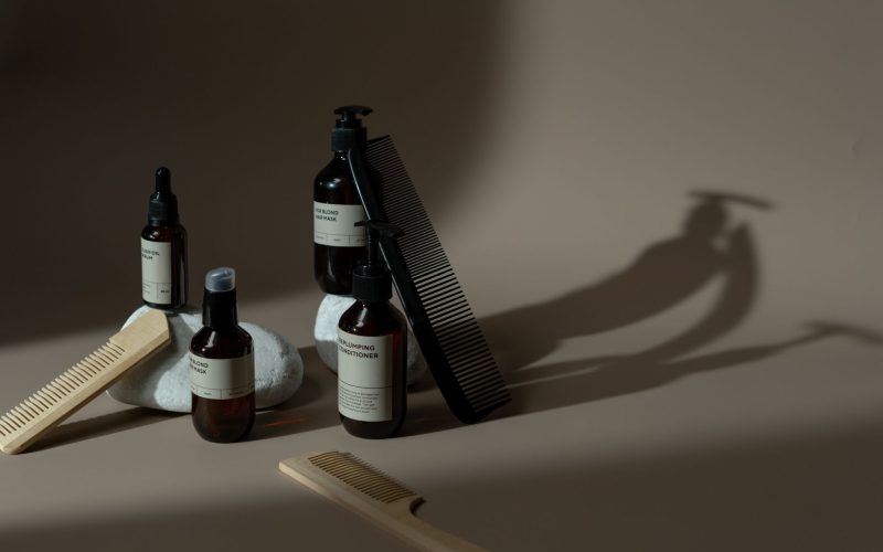 Flacons de soin pour barbe et peigne posés sur une table, en lumière douce
