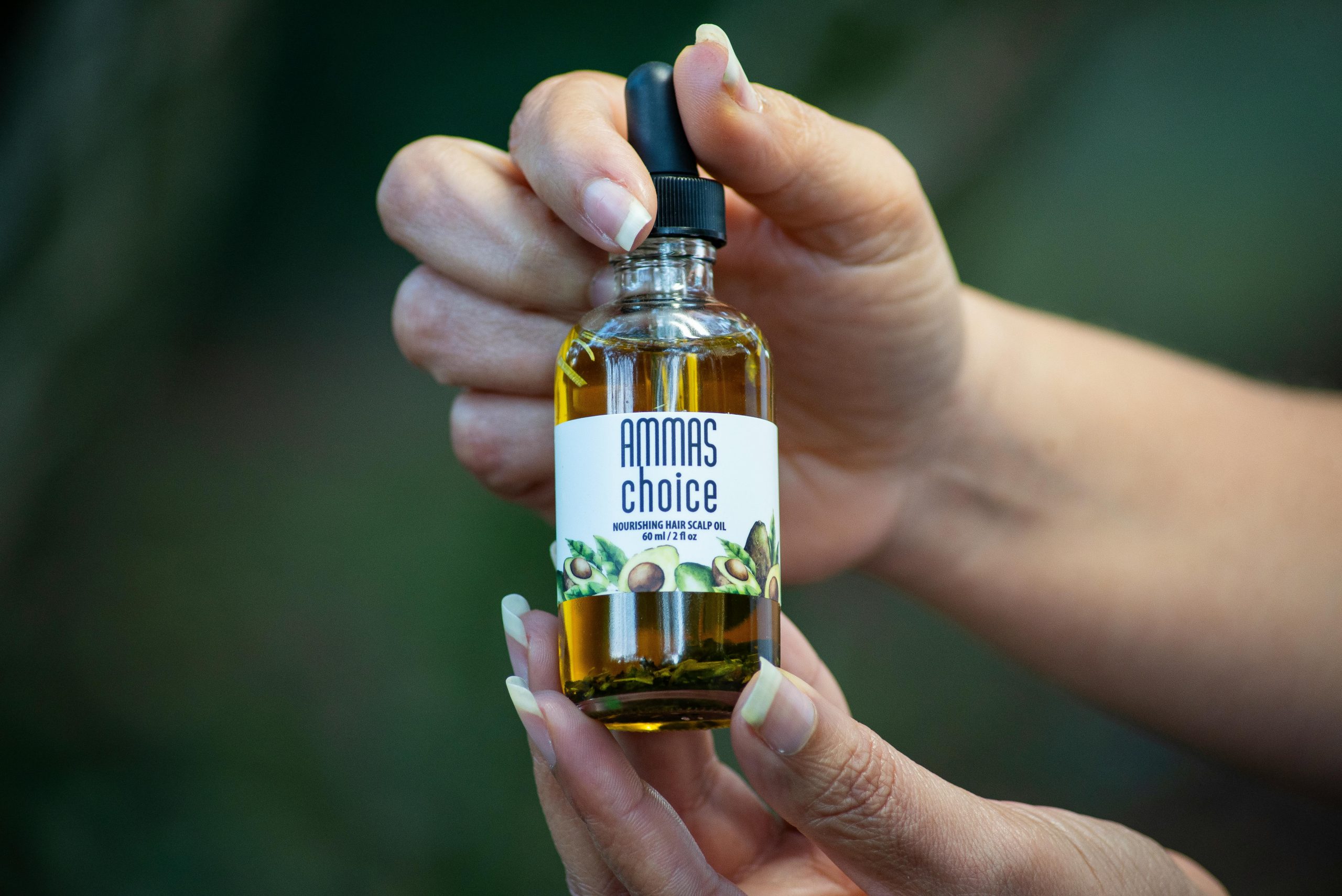 Close-up de mains tenant un flacon d'huile pour le cuir chevelu.