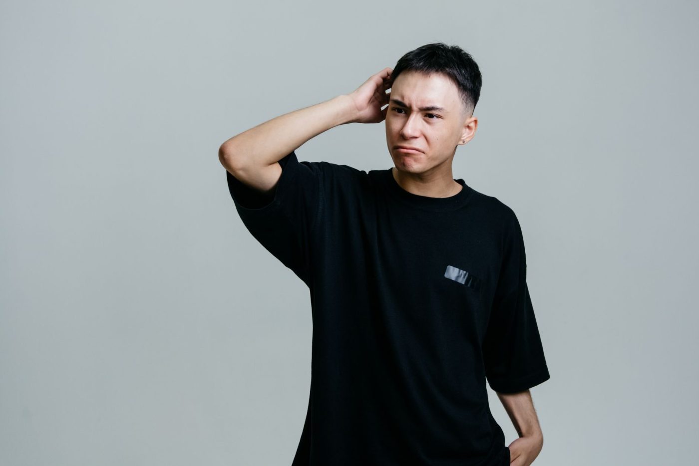 Jeune homme en tee-shirt noir qui se gratte la tête