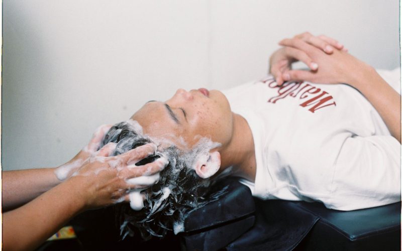 Homme allongé au bac pendant qu'on lui fait un shampoing au salon