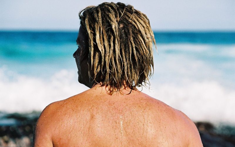 Homme aux cheveux blonds mouillés, de dos face à la mer