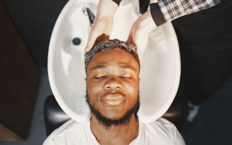 Homme au bac à shampoing chez le coiffeur, les yeux fermés