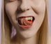 Close-up portrait of a blonde woman with her tongue out against a neutral background. Gros plan portrait d'une femme blonde avec la langue sortie sur un fond neutre.