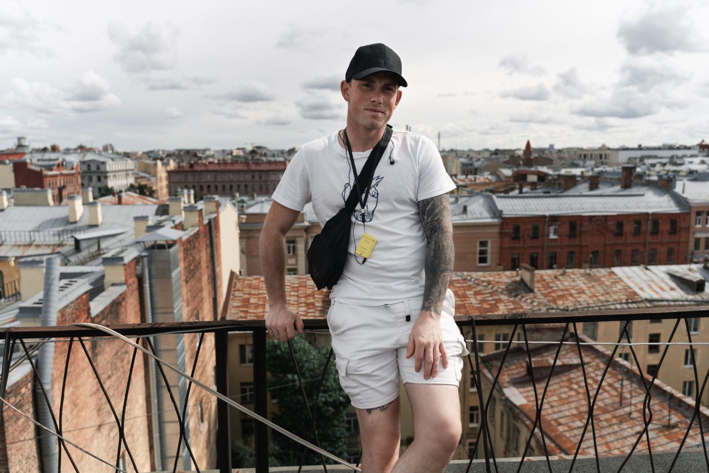 Homme en tenue d'été blanche, tee-shirt et short assortis, sur une terrasse en ville