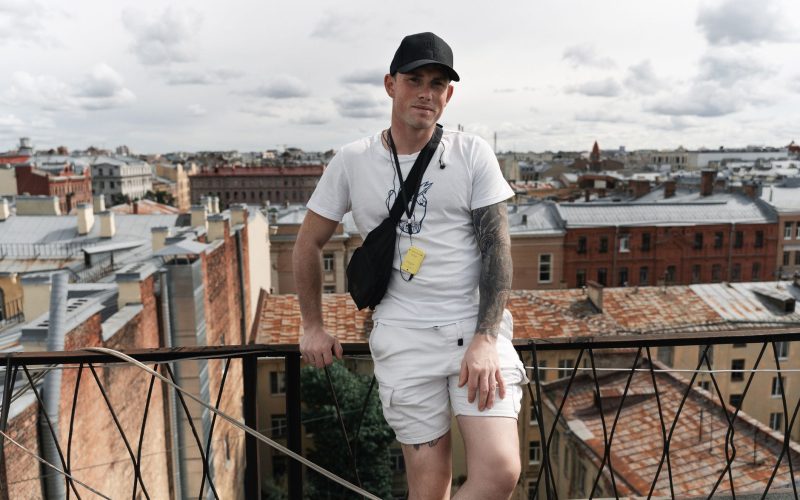 Homme en tenue d'été blanche, tee-shirt et short assortis, sur une terrasse en ville