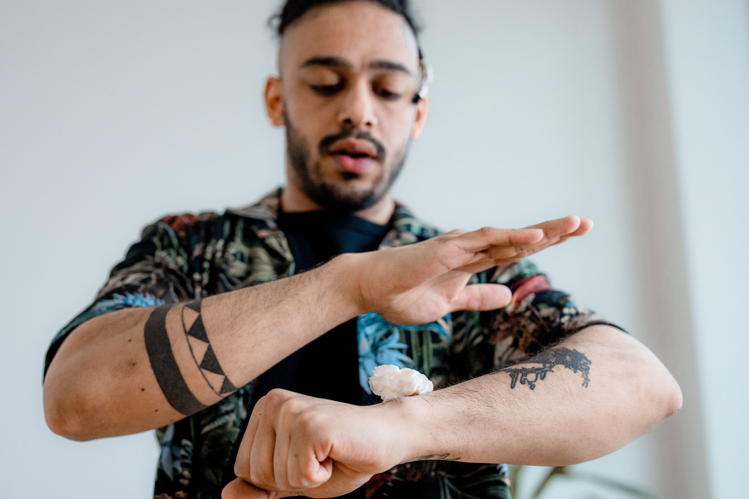 Combien coûte vraiment un tatouage homme avant-bras ? 7 A man with tattoos applies cream to his forearm, highlighting tattoo care and skincare routines. Un homme tatoué applique de la crème sur son avant-bras, mettant en évidence les soins des tatouages et les routines de soins de la peau.