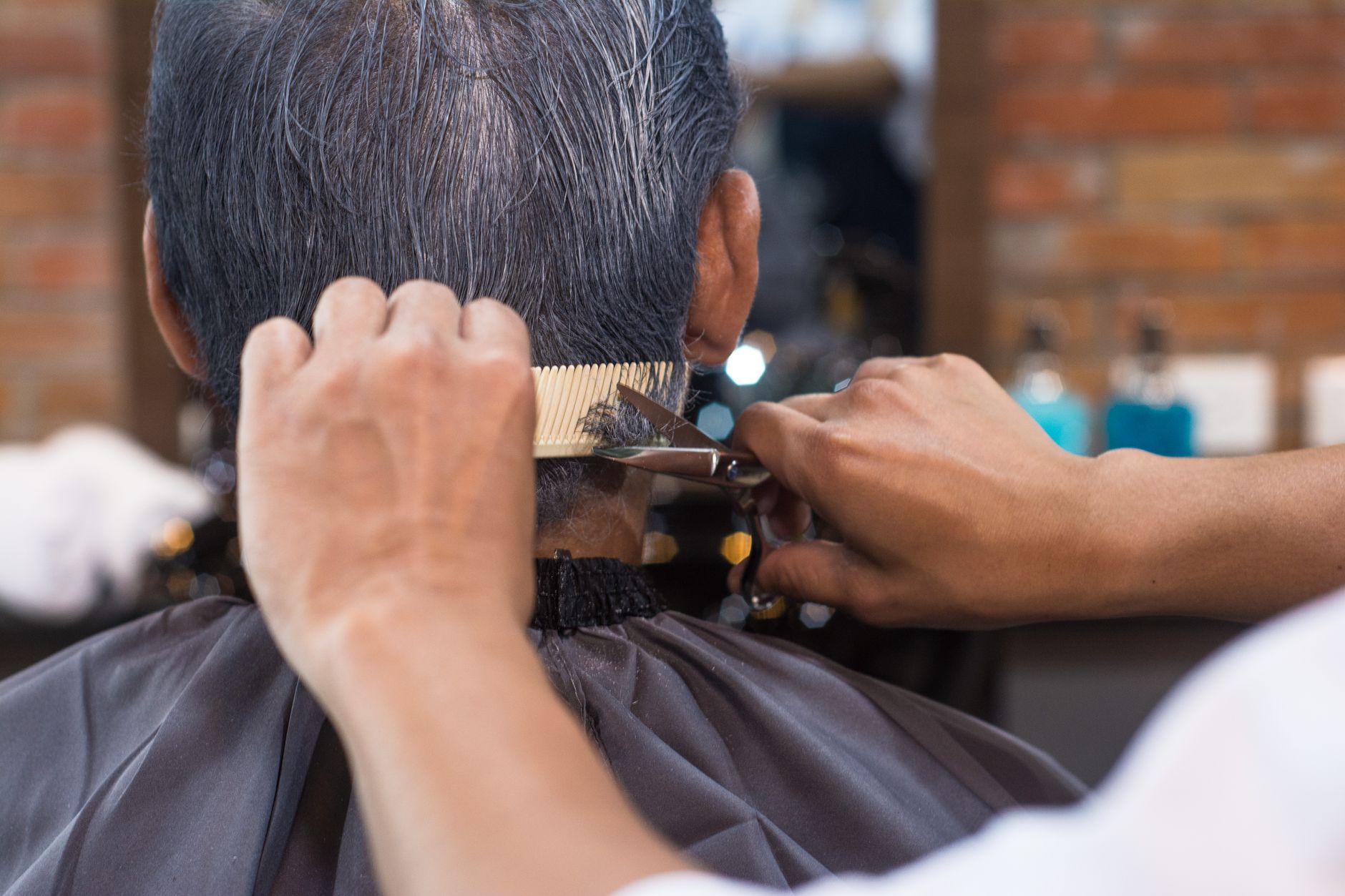 Barbier taillant les cheveux aux ciseaux et au peigne