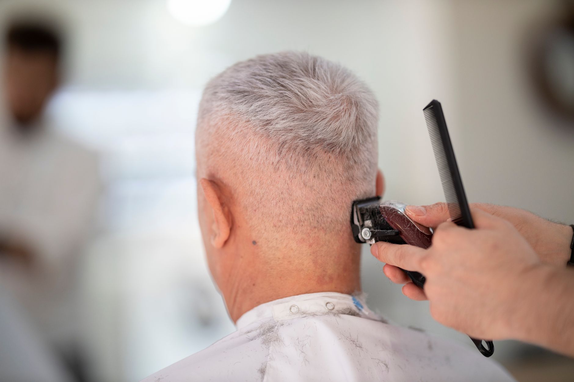 Homme aux cheveux gris se faisant coiffer chez le barbier