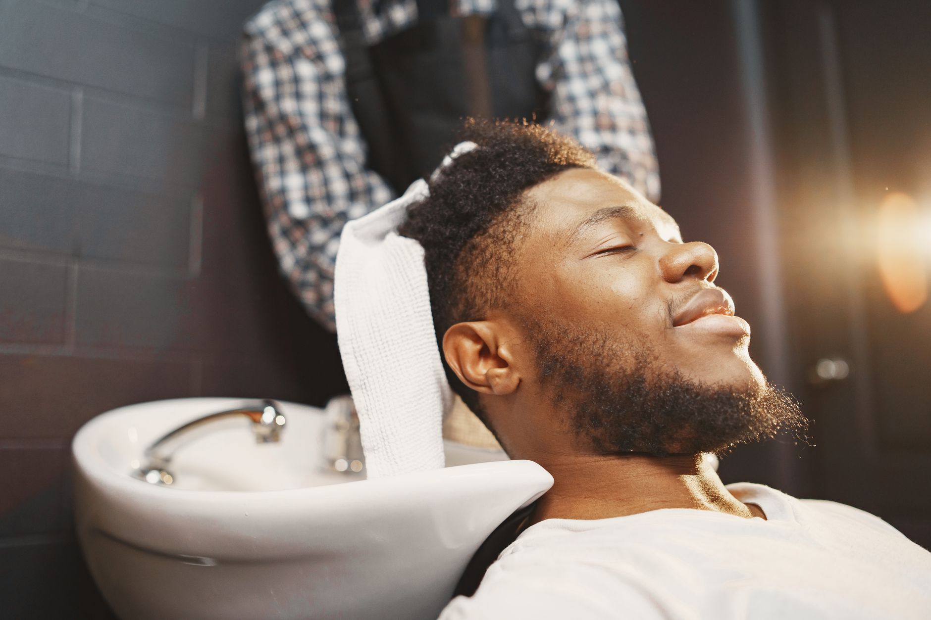Cheveux gras homme : arrête ces gestes qui aggravent tout 4 Homme détendu pendant un rinçage chez le barbier