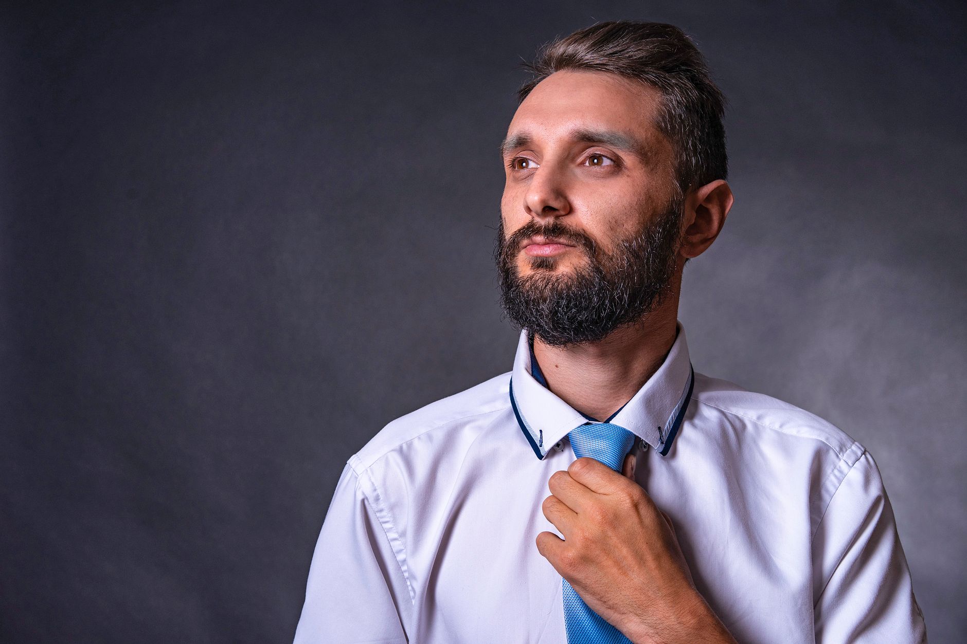 Comment t'habiller pour un enterrement sans te tromper ? 2 Homme ajuste sa cravate sombre