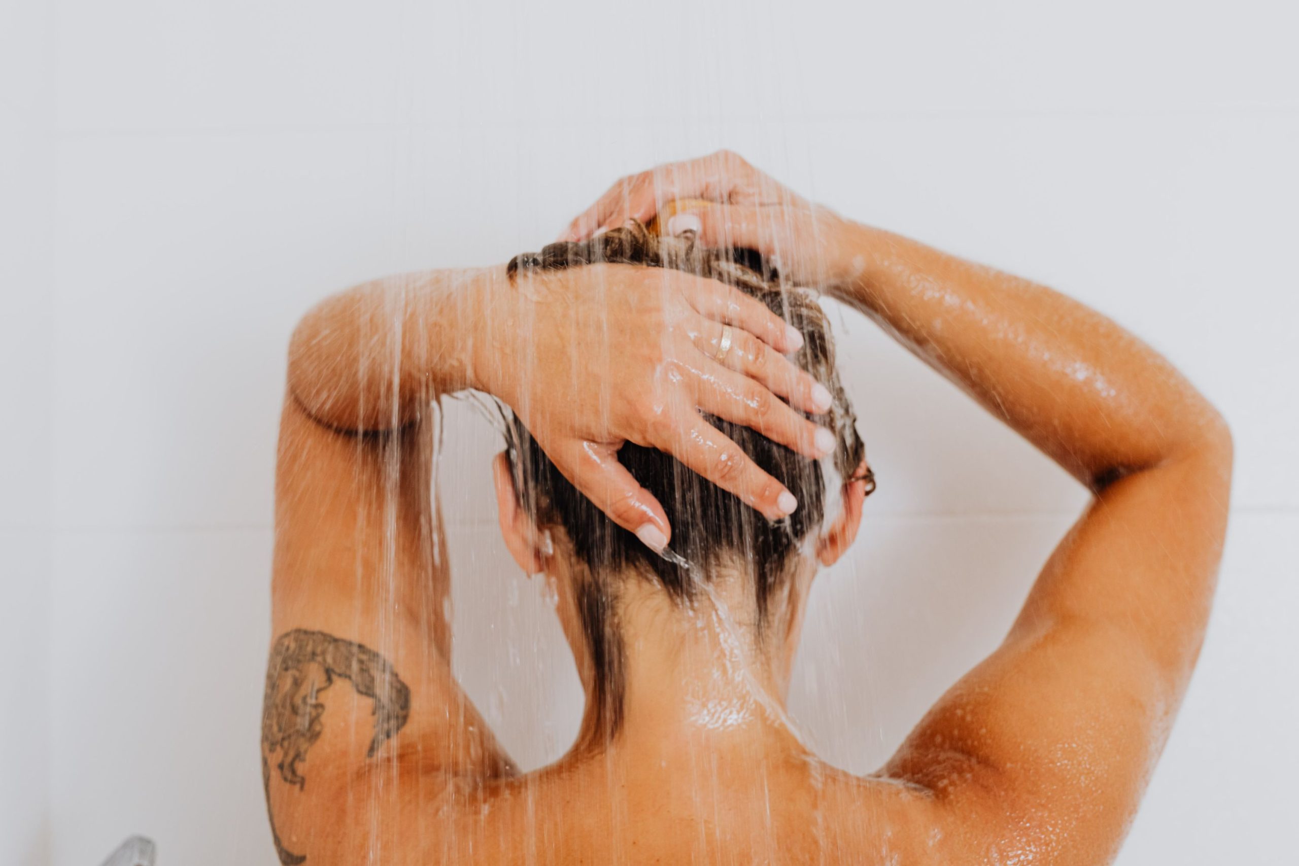 Homme sous la douche qui se lave les cheveux