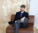 Homme elegant en costume marron assis sur un canape