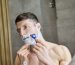 Homme se rasant le visage avec un rasoir devant un miroir