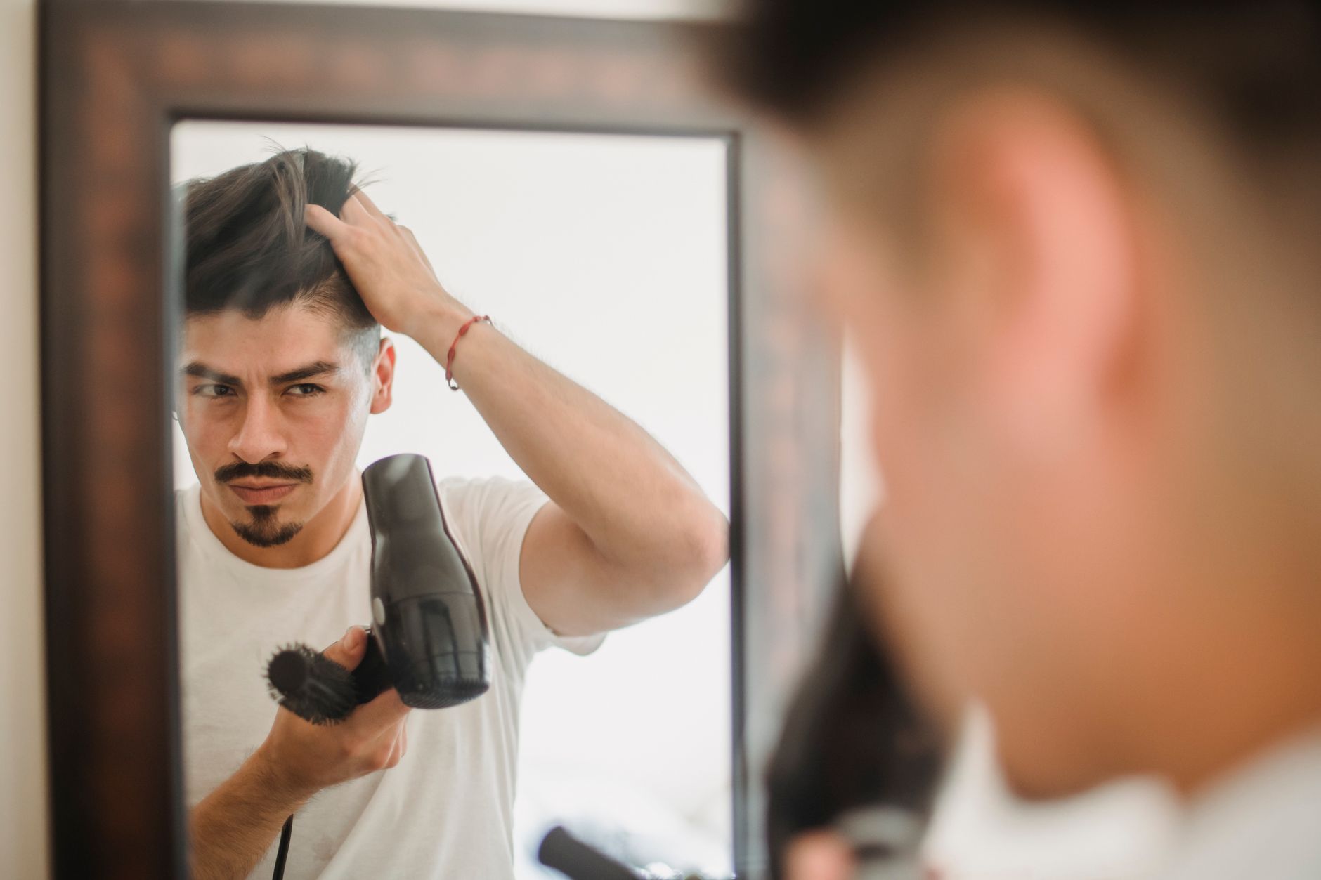 Lave-toi bien les cheveux : la méthode qui marche 2 Homme qui coiffe ses cheveux devant un miroir
