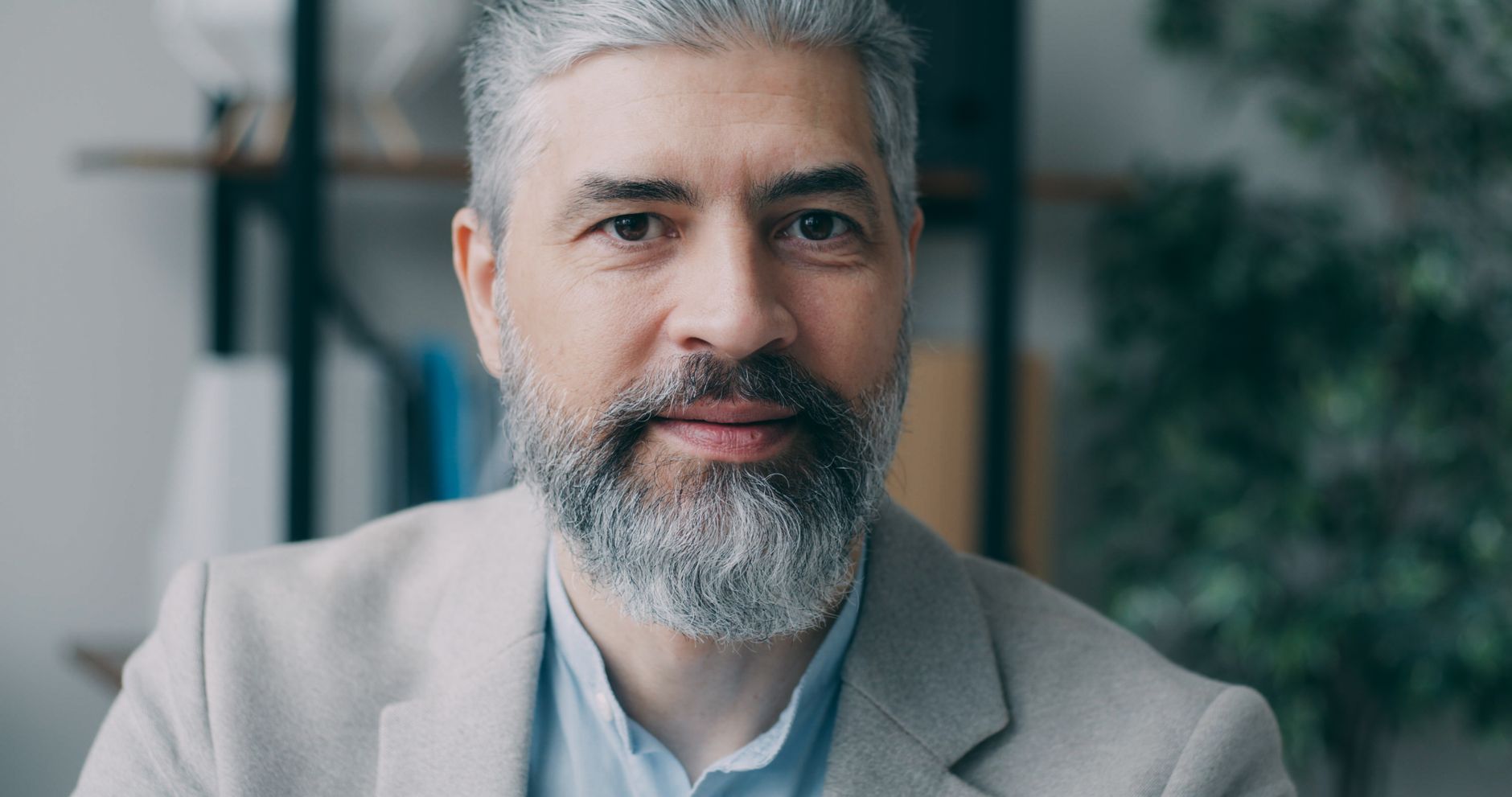 Homme mûr à la barbe grise courte et soignée, veste claire