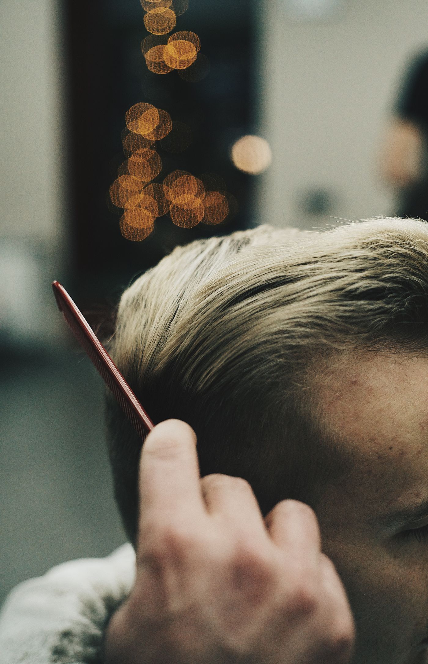 Peigne rouge couchant vers l'arrière les cheveux blonds du côté d'une tête d'homme