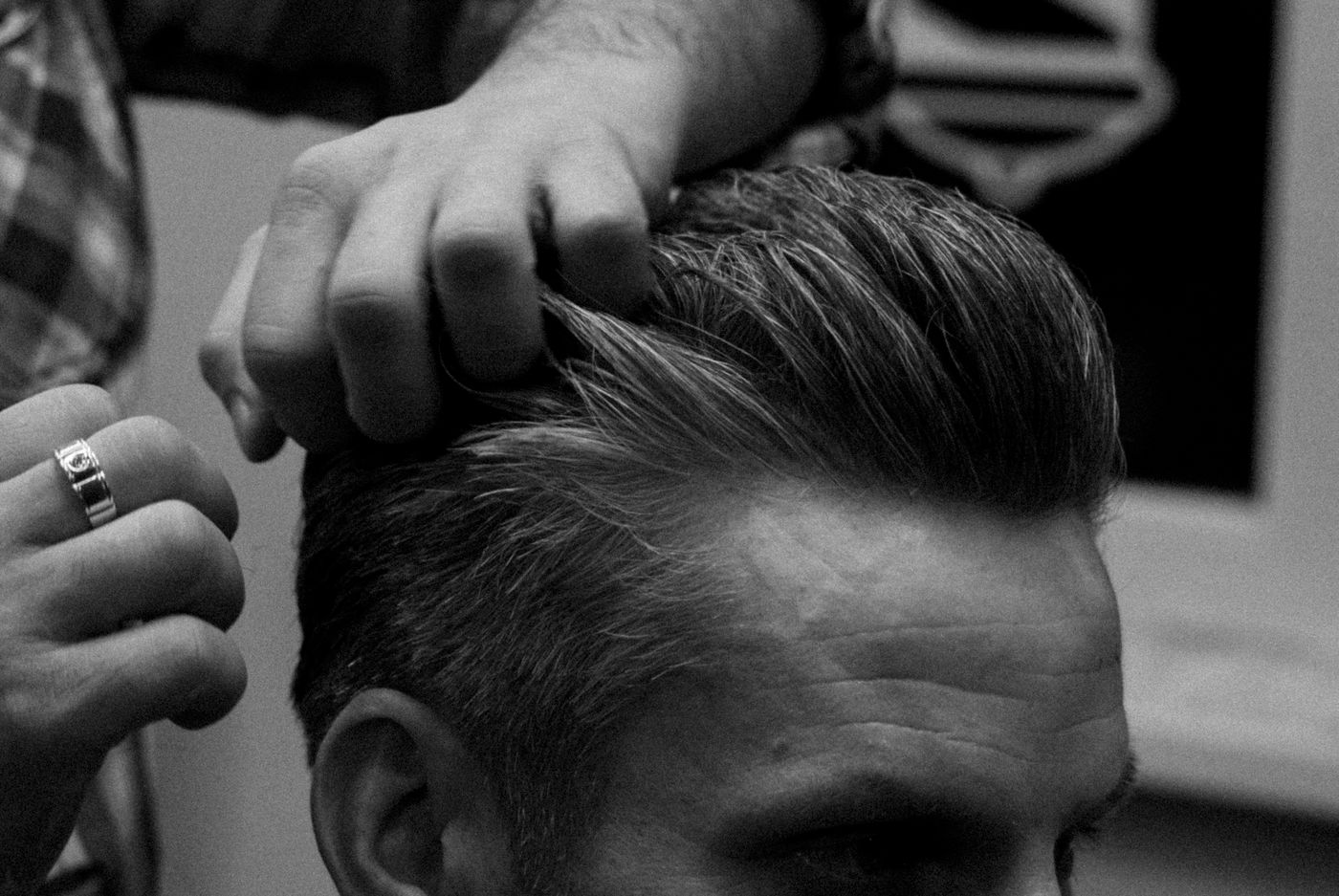 Doigts d'un barbier qui mettent en forme le dessus d'une coupe, en noir et blanc