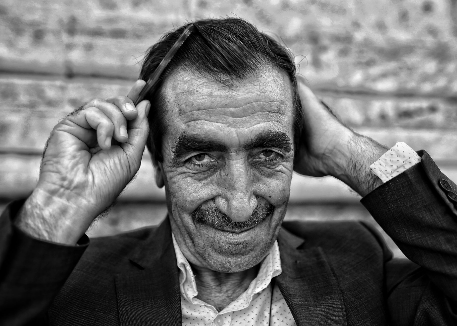 Homme âgé qui coiffe ses cheveux avec un peigne fin, en noir et blanc