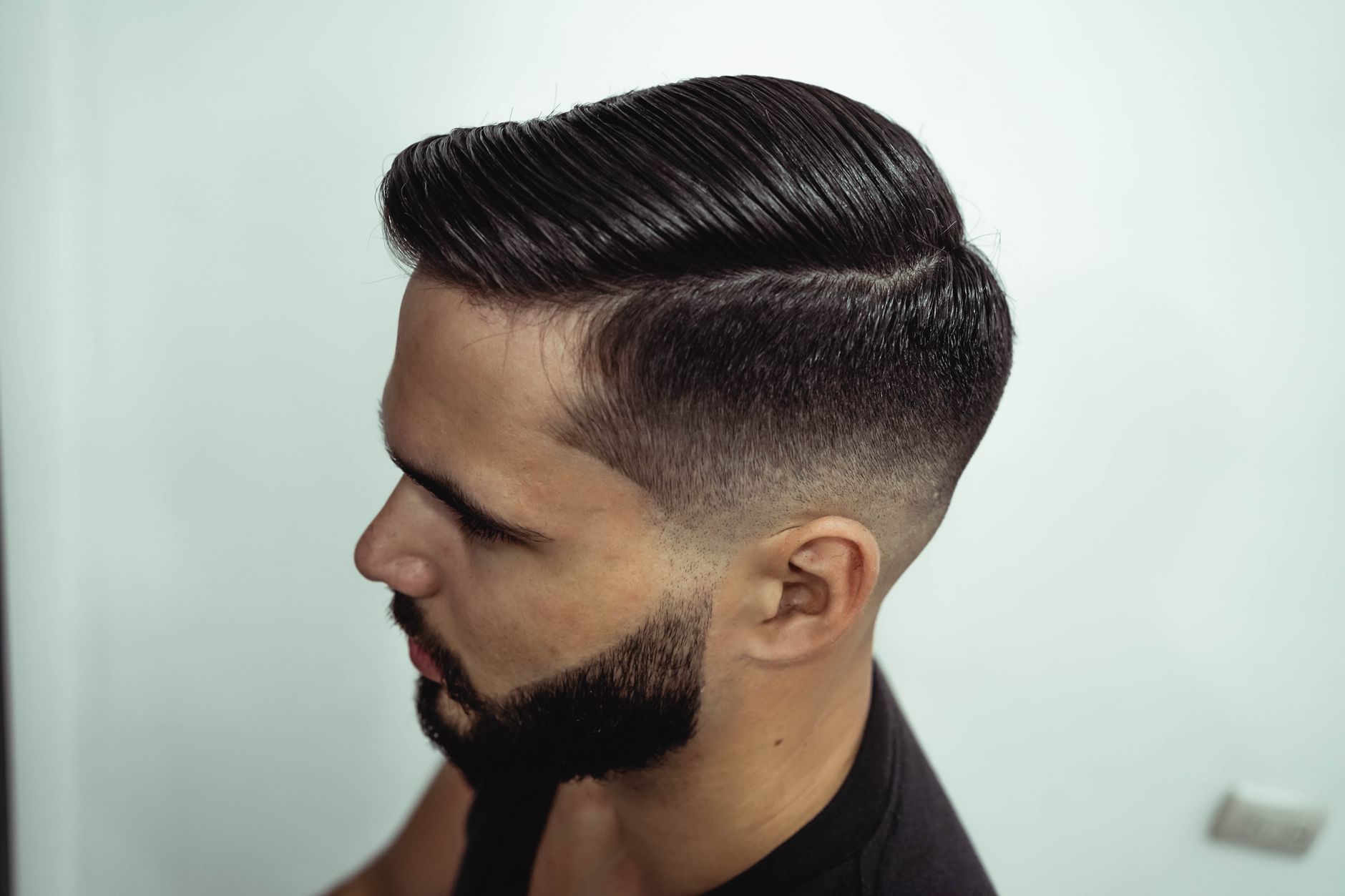 Homme de profil, cheveux peignés sur le côté avec raie nette et côtés en dégradé