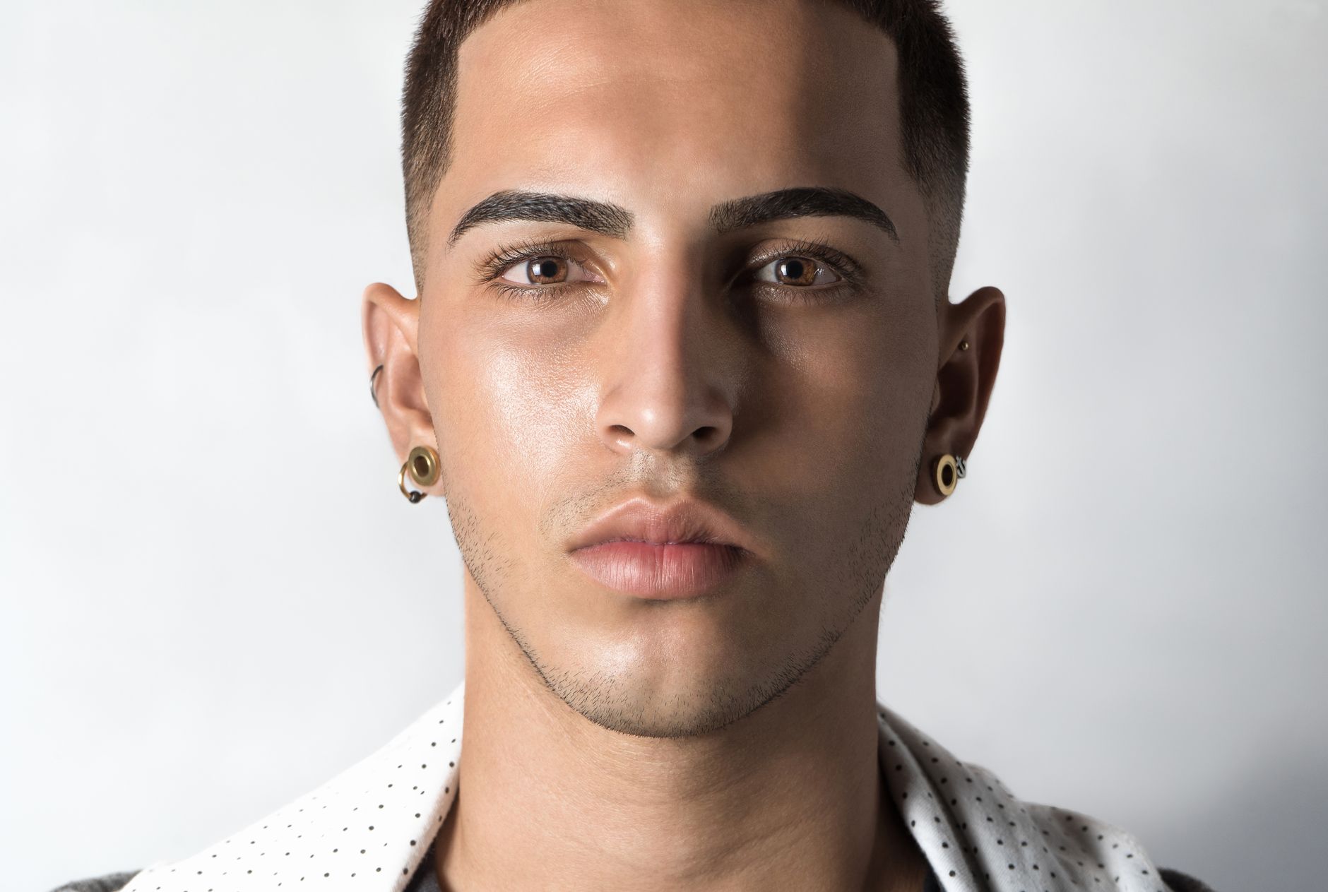 Homme de face aux cheveux courts, dessus court et côtés dégagés, sur fond blanc