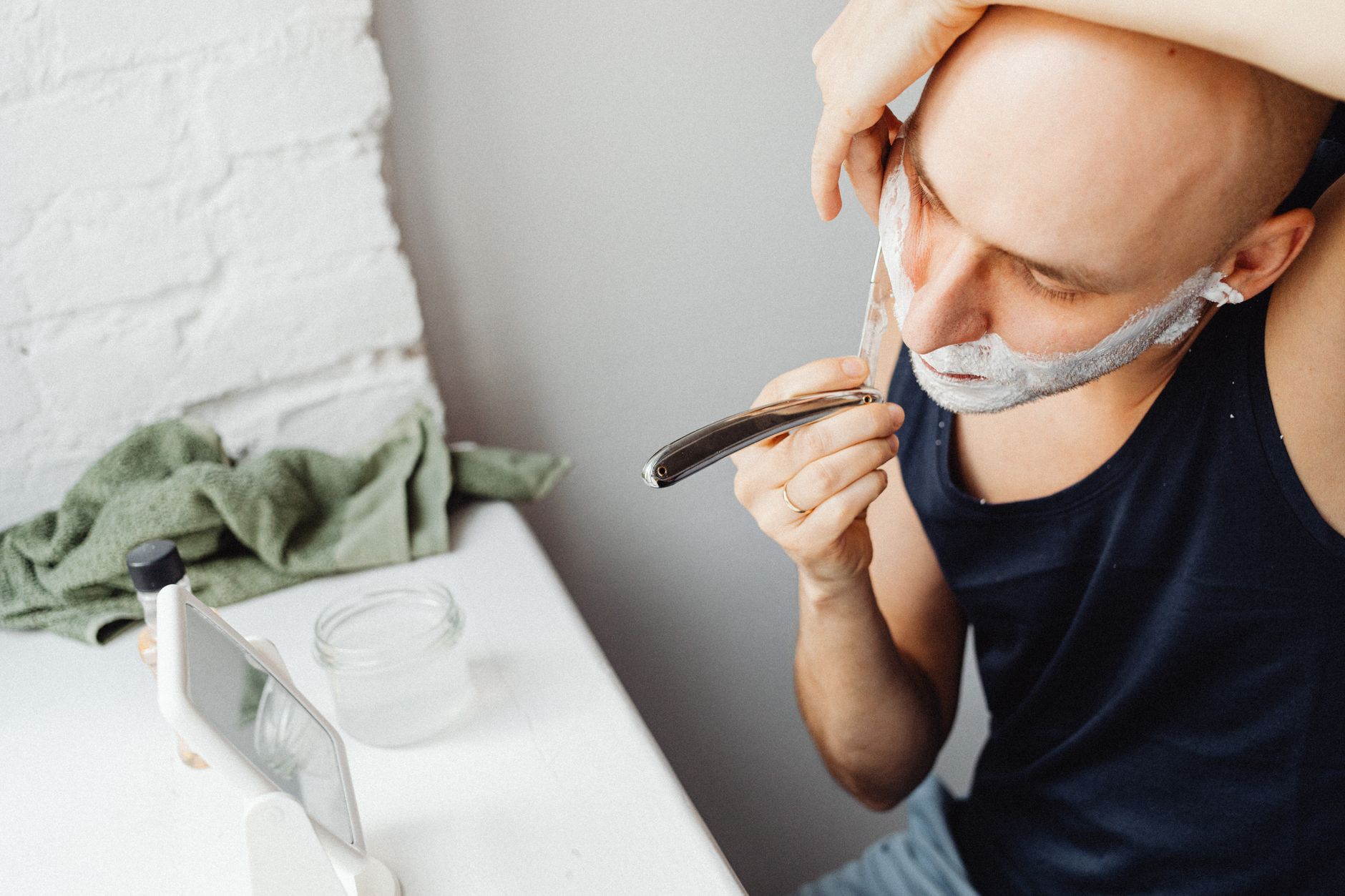 Homme qui se rase le crâne au rasoir droit devant un miroir