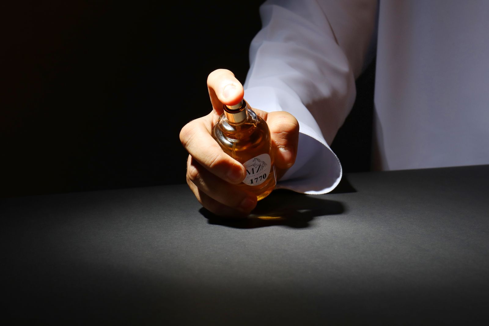 Boisé, fougère, aromatique : décrypter la fiche d'un coffret homme avant de l'offrir 3 Main qui tient un flacon de parfum homme