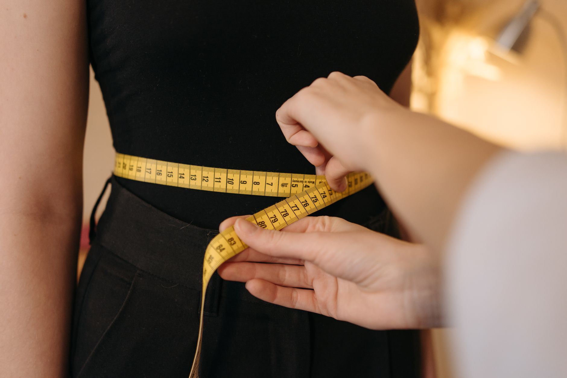 Mains qui mesurent un tour de taille au mètre ruban