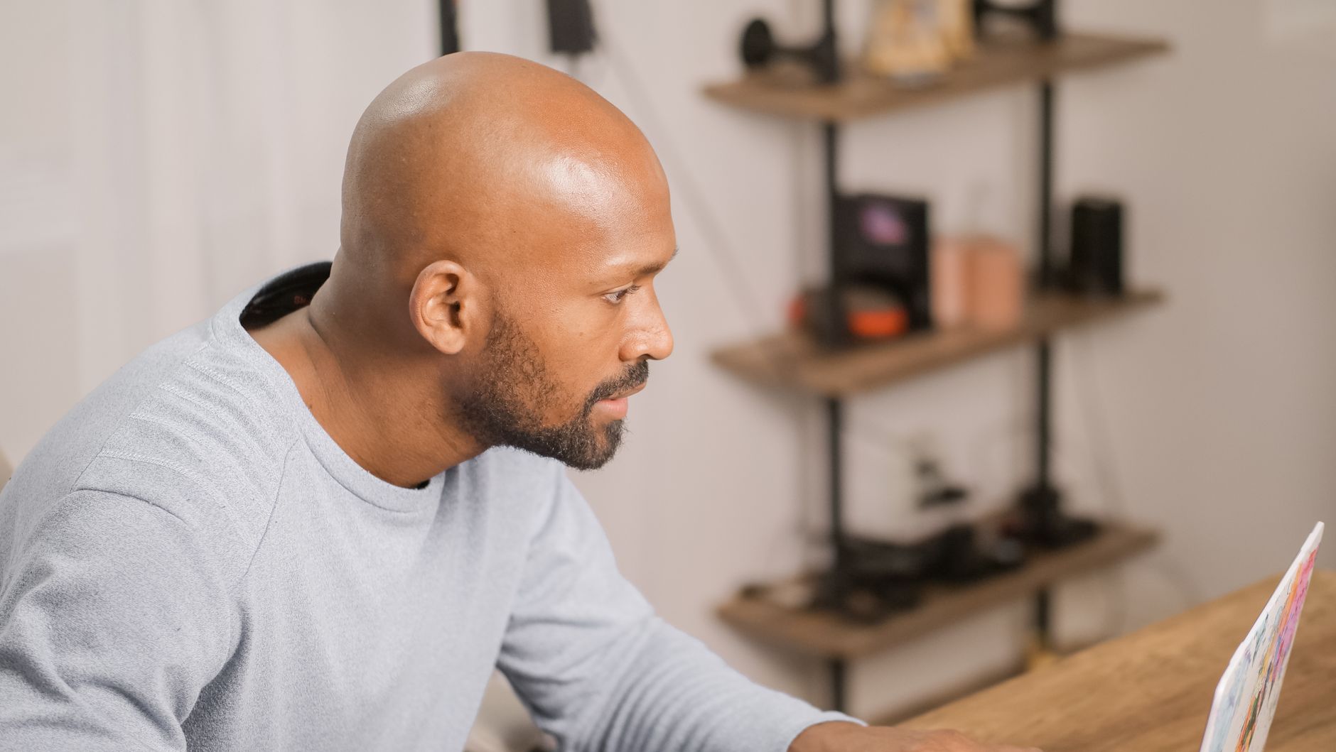 Homme au crâne lisse et à la barbe courte, de profil à son bureau