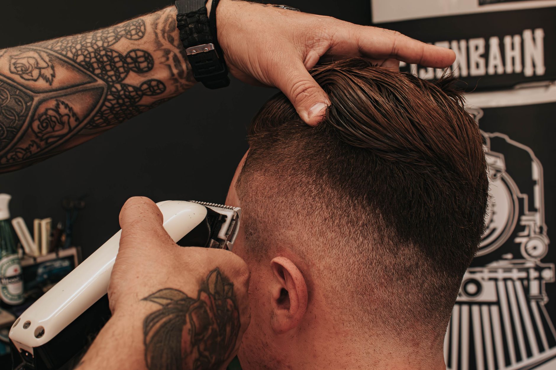 Barbier qui tond l'arrière d'un client en tenant le dessus