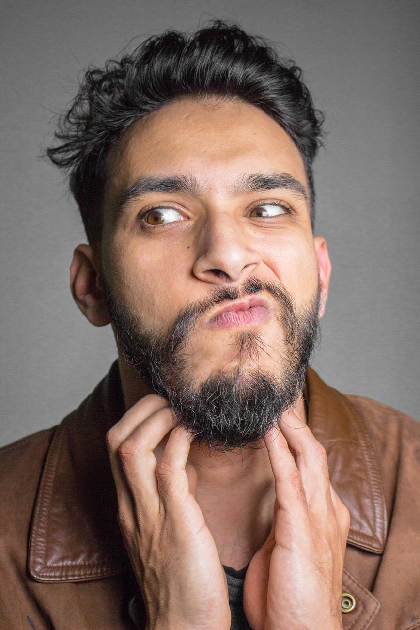 Homme barbu qui se tient le menton, l'air perplexe, veste en cuir