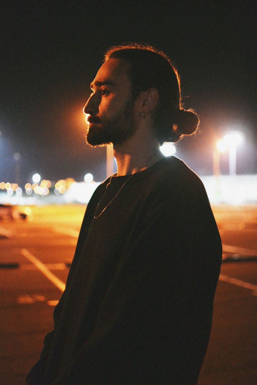 Homme barbu de profil, cheveux longs attachés en arrière, de nuit