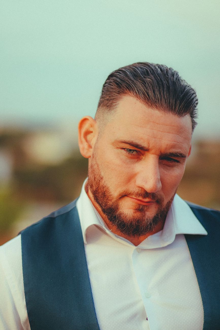 Homme à la barbe moyenne soignée, gilet bleu, de trois quarts