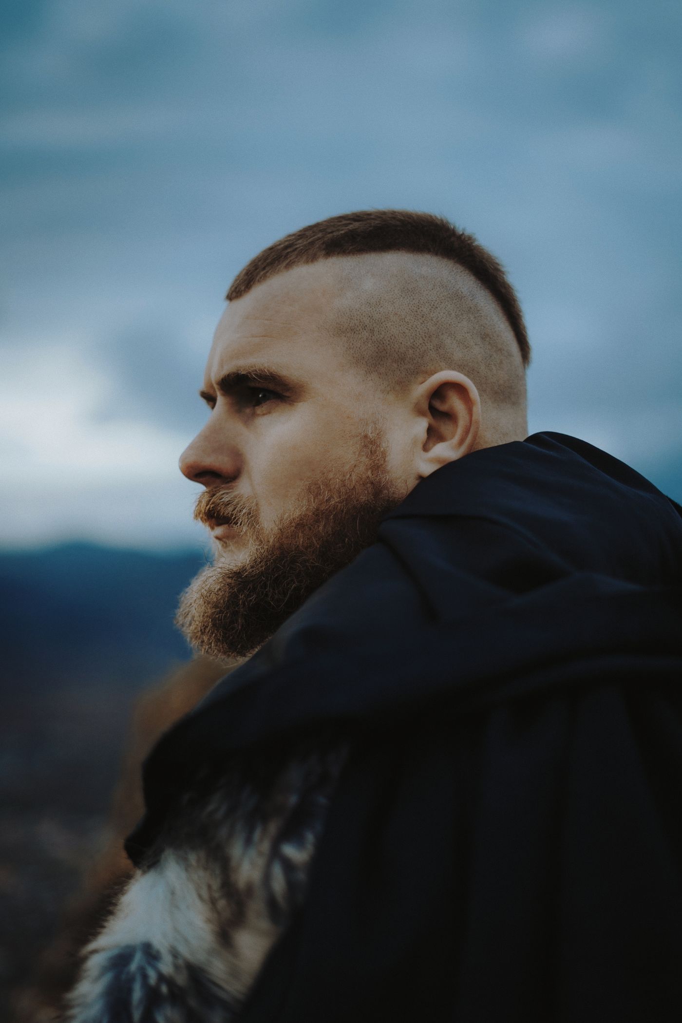 Homme barbu de profil, côtés rasés et courte bande de cheveux sur le sommet