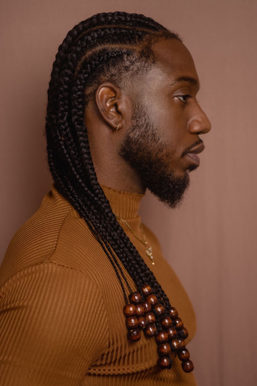 Homme barbu de profil aux longues tresses ornées de perles