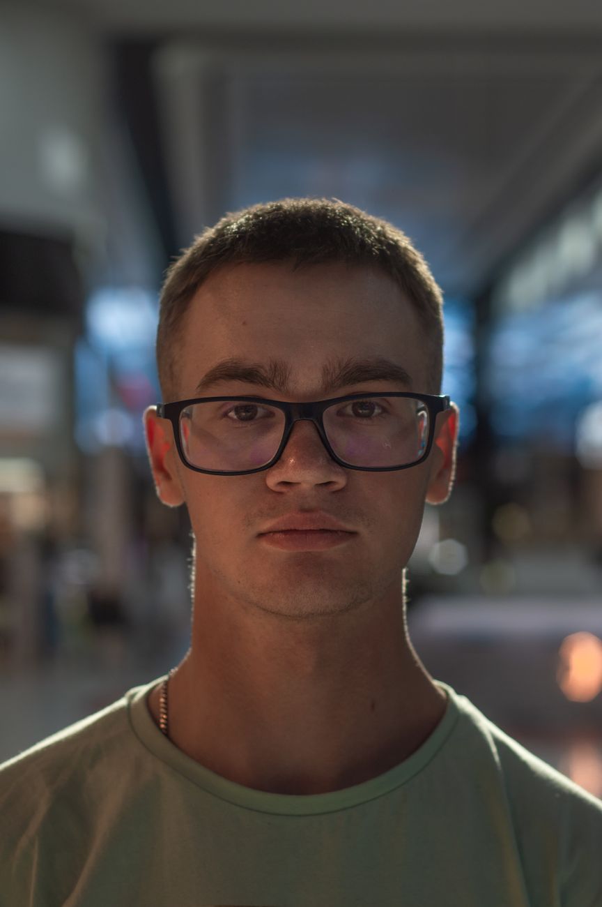 Jeune homme à lunettes, cheveux courts tombant en petite frange sur le front