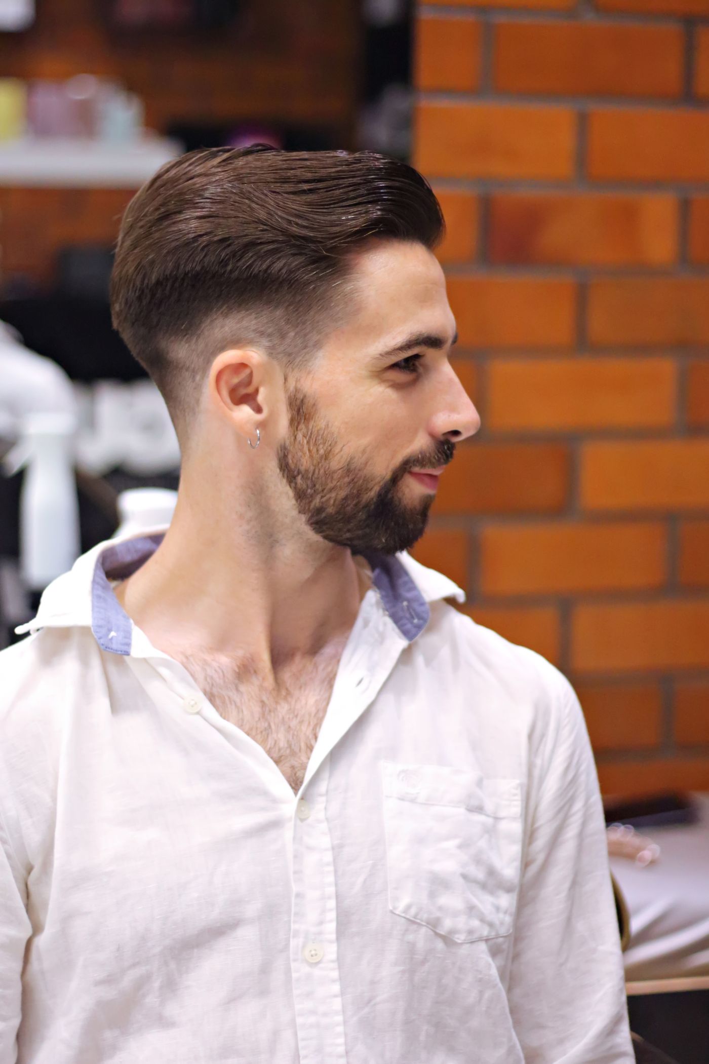 Homme barbu de profil en chemise blanche, dégradé sans démarcation et dessus coiffé en arrière