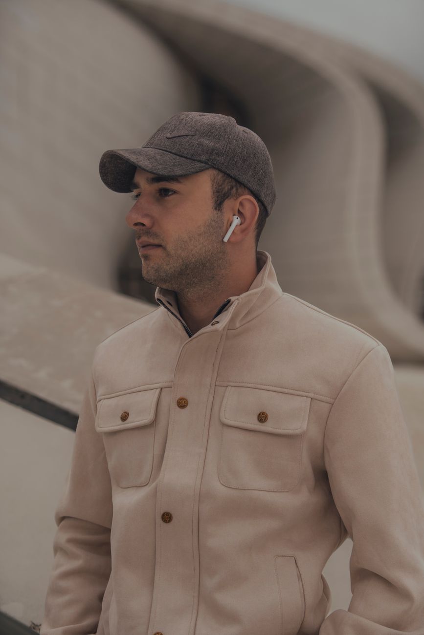 Homme à la casquette unie et à la barbe courte, veste beige, de trois quarts