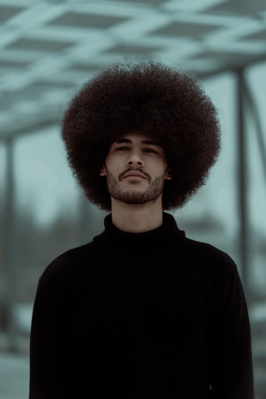 Homme à l'afro rond et à la barbe courte, col roulé noir