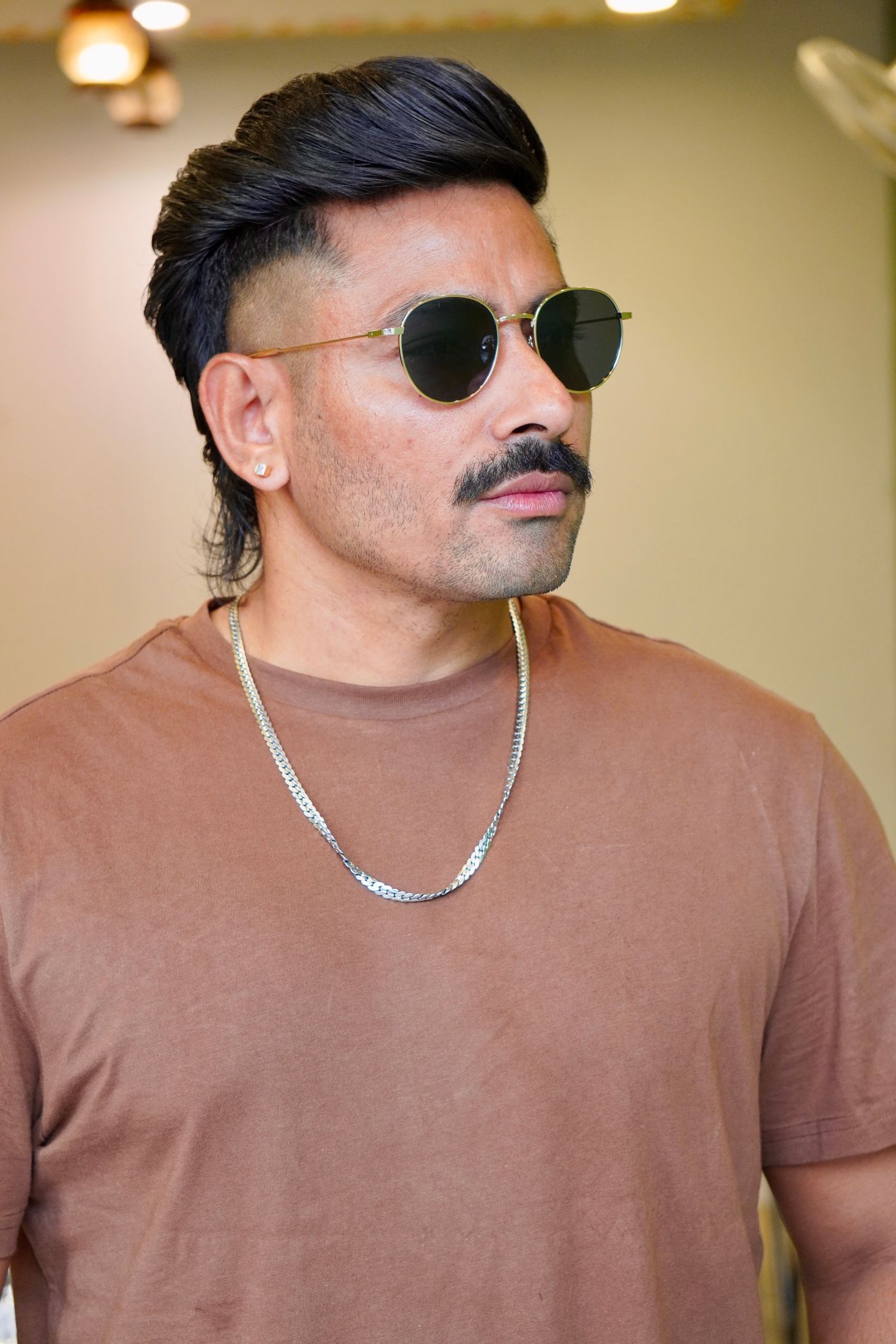 Homme à lunettes rondes portant un mulet moderne, tempes rasées et nuque longue