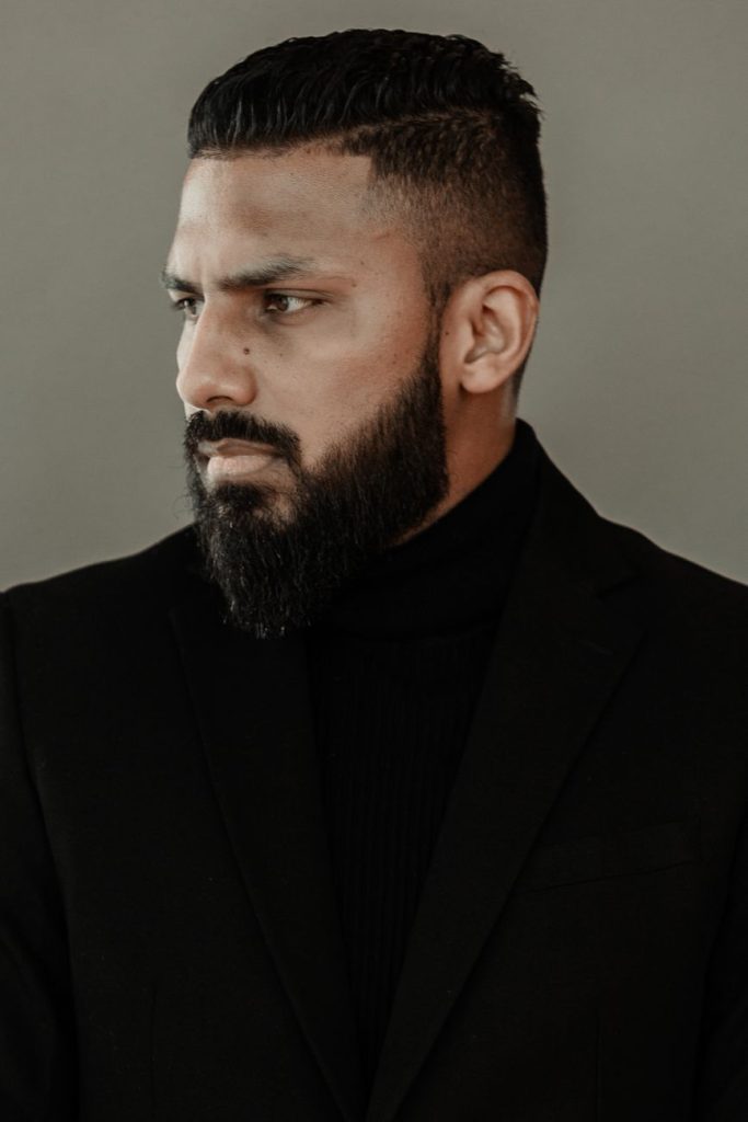 Homme à la barbe moyenne bien dessinée, de trois quarts sur fond sombre