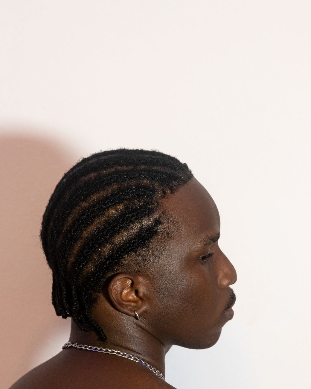 Homme de profil aux tresses collées courtes, nuque dégagée
